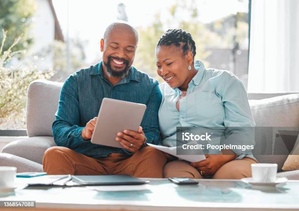 Shot Of A Mature Couple Looking Through Their Bills While Using A Digital Tablet Stock Photo - Download Image Now