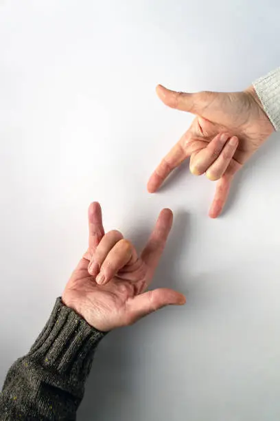 The phrase I-Love-You in sign language, the language of the deaf. Male and female hands on white background, copy space.