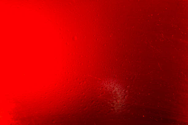 Texture created in a glass with water drops on red background.