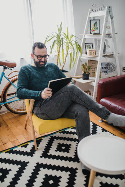 istock Shot of a man using his tablet while relaxing on the couch at home 1368549950