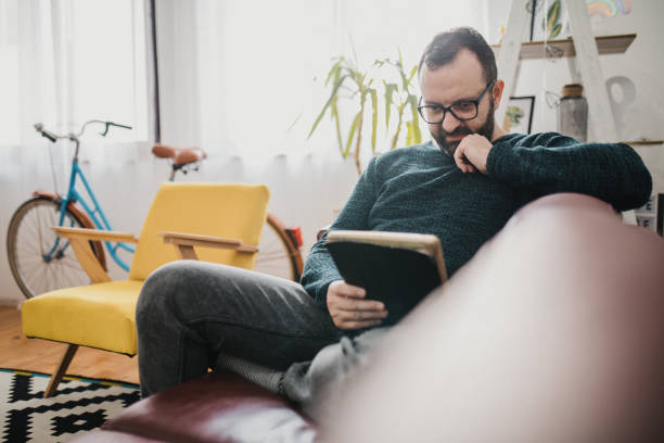 istock Shot of a man using his tablet while relaxing on the couch at home 1368549979