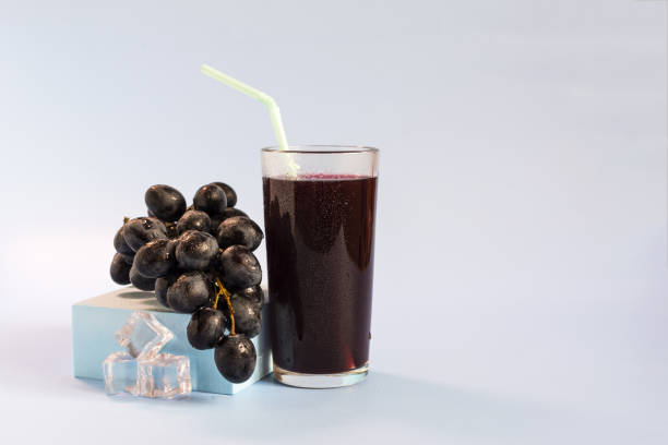 A vine and a glass of grape juice on a light background close-up.