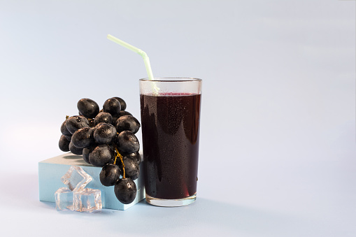 A vine and a glass of grape juice on a light background close-up.