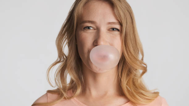 bastante divertida chica felizmente soplando chicle aislado en blanco ba - chewing gum women bubble blowing fotografías e imágenes de stock