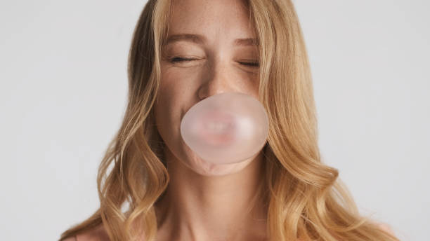 cerrar hermosa chica divertida felizmente soplando chicle aislado - chewing gum women bubble blowing fotografías e imágenes de stock