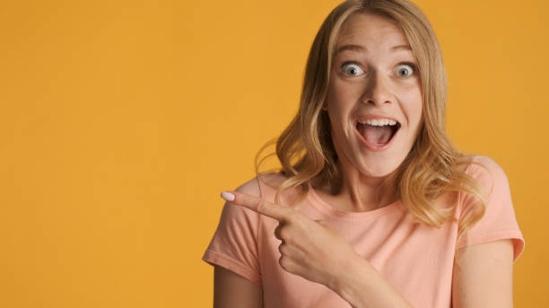 istock Amazed girl surprisingly indicates on copy space for text or pro 1368552876