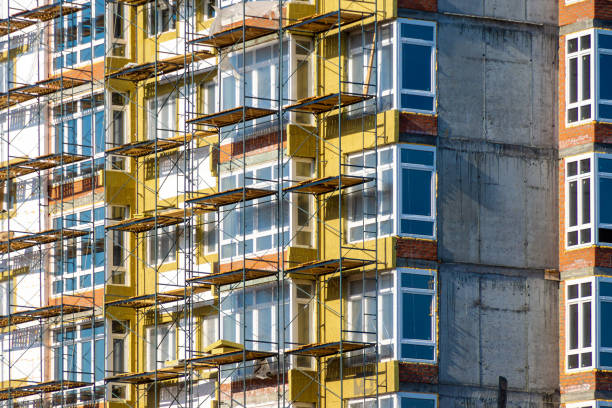 lavori di costruzione in quota durante l'isolamento della facciata da ponteggi o messa in scena - cladding foto e immagini stock