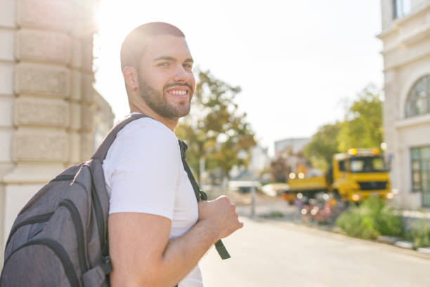 istock Happy young man with backpack walking on sunshine 1368556188