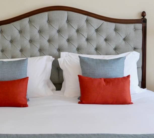Luxury bed with wooden framed headboard and cushions in grey and red