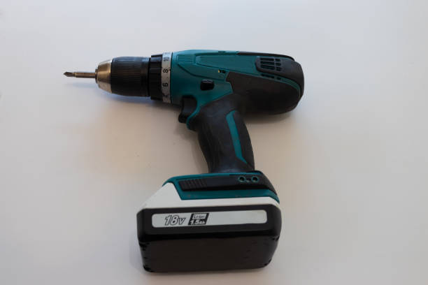 istock Hand with cordless screwdriver and drill on white background. Twists screws into the board. Selective focus 1368557909