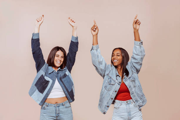 istock Two cheerful female friends having fun with arms raised up at studio 1368558955