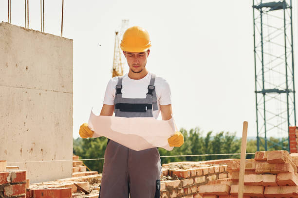 istock Holding document. Young construction worker in uniform is busy at the unfinished building 1368559134