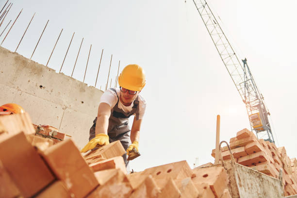 istock Using bricks. Young construction worker in uniform is busy at the unfinished building 1368559153