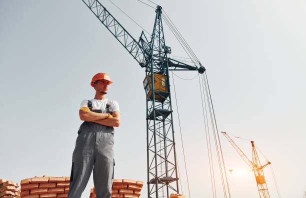 istock With crane at background. Young construction worker in uniform is busy at the unfinished building 1368559231
