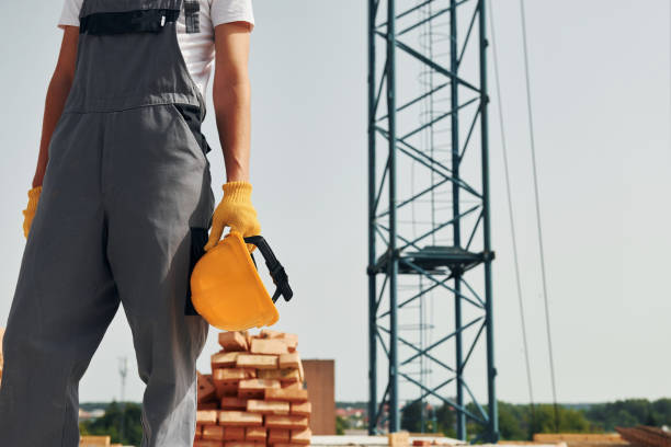 istock Close up view. Young construction worker in uniform is busy at the unfinished building 1368559256