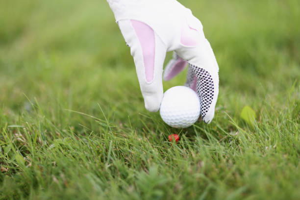 The head of a steel golf club showing motion blur as it approaches a golf ball in the rough..