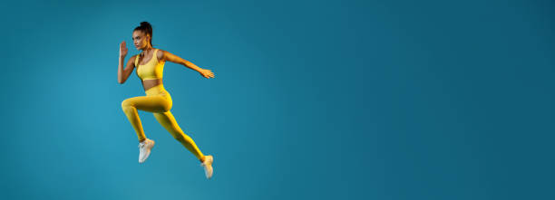 istock Athletic Female Jumping Running In Mid-Air Looking Aside, Blue Background 1368559791