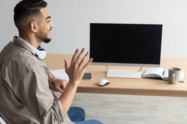 istock Arab man waving hand at blank empty computer monitor 1368559875
