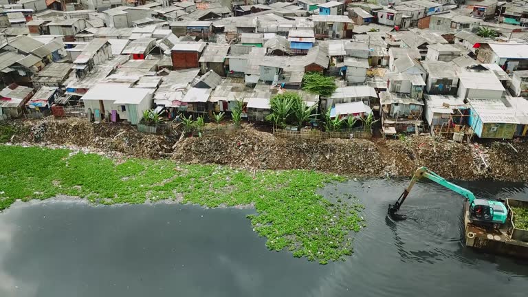 Excavator and crowded slum houses on lakeside