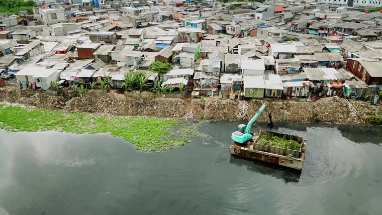 View of excavator and slum houses on lakeside