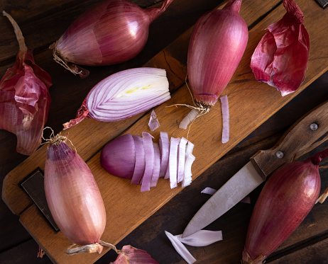 Sliced Red tropea onions with a knife on a wooden board top view