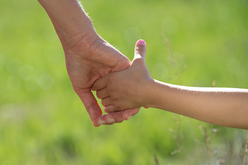 Close-up of mother and daughter holding hands in agricultural field.
