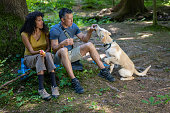 Mature couple relaxing with their pet dog in forest
