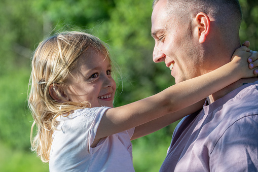 Close-up of smiling father and daughter embracing each other in agricultural field.