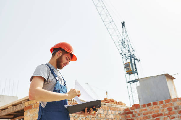 istock Some paperwork. Young construction worker in uniform is busy at the unfinished building 1368566939