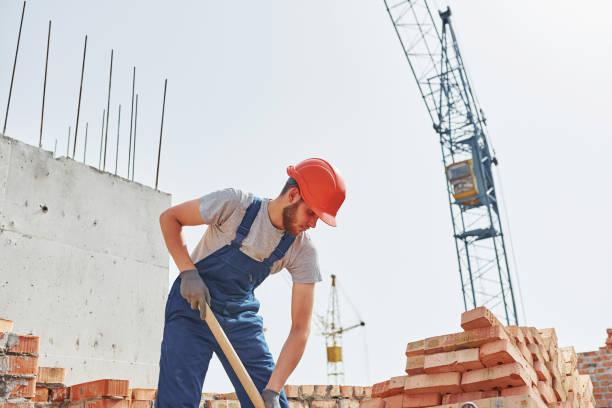 istock Using a showel. Young construction worker in uniform is busy at the unfinished building 1368566960