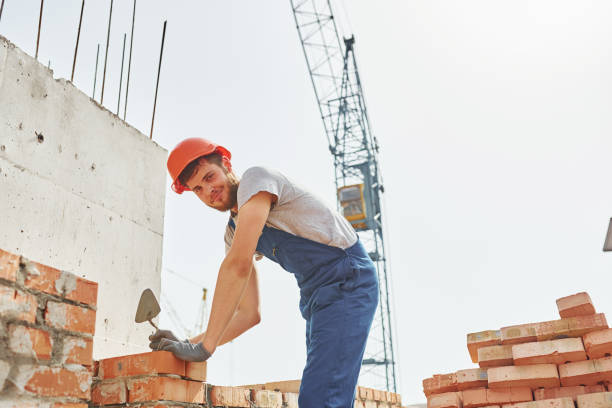 istock Holding bricks. Young construction worker in uniform is busy at the unfinished building 1368566966