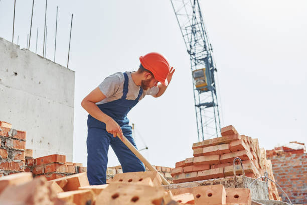 istock Using a showel. Young construction worker in uniform is busy at the unfinished building 1368566974