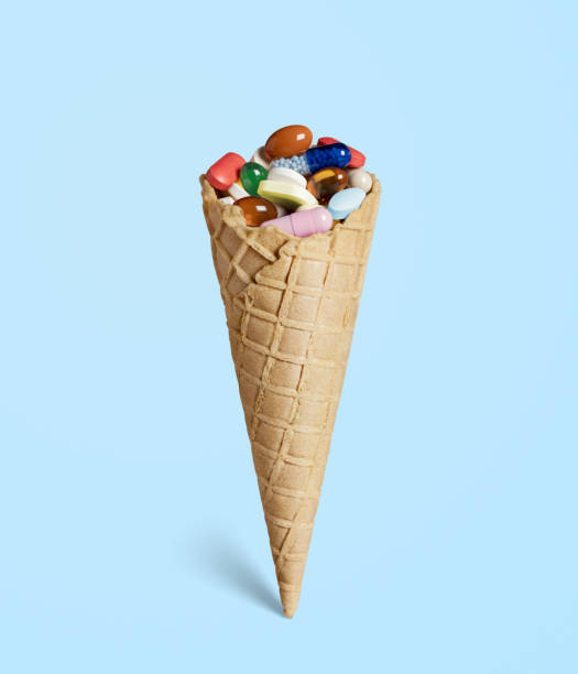 istock Ice cream waffle cone with colorful pills on blue 1368567860