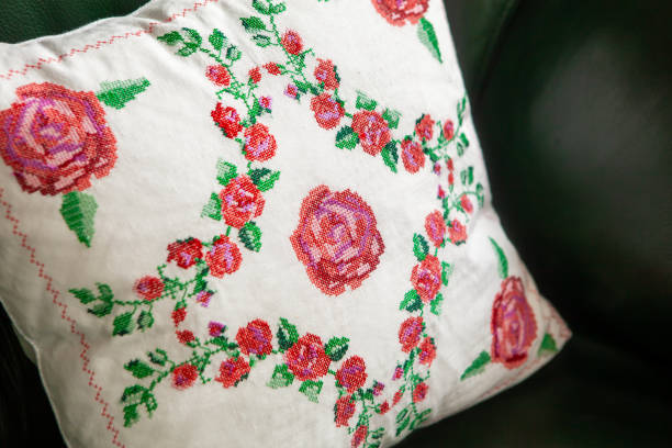 istock Handmade decorative pillow with rose embroidery on a green leather sofa. 1368568455