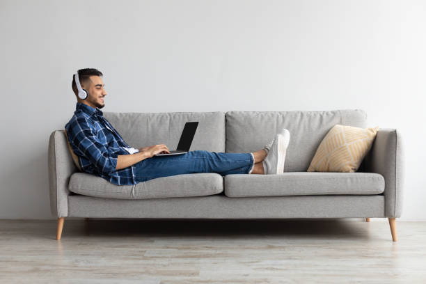 Smiling Arab man in headphones using pc at home