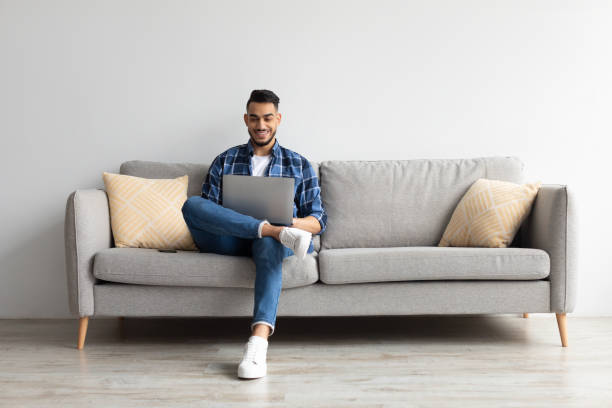 istock Portrait of smiling Arab man using laptop at home 1368568608