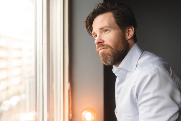 istock Man looking out through the window at home 1368569295