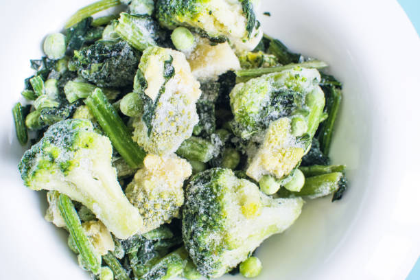 istock Frozen green vegetables with ice crystals on a light plate top view 1368570929