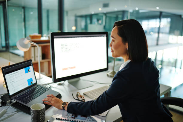 aufnahme einer jungen geschäftsfrau mit einem computer in einem modernen büro bei der arbeit - businesswoman using computer computer monitor women stock-fotos und bilder