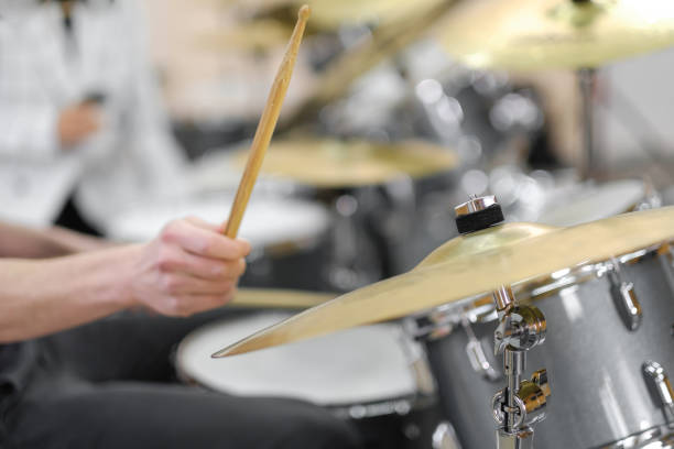 Young adult men and women learn to play drums at school. Hobbies and pastime. stock photo