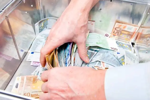 Photo of Hands grabbing money from a cash box