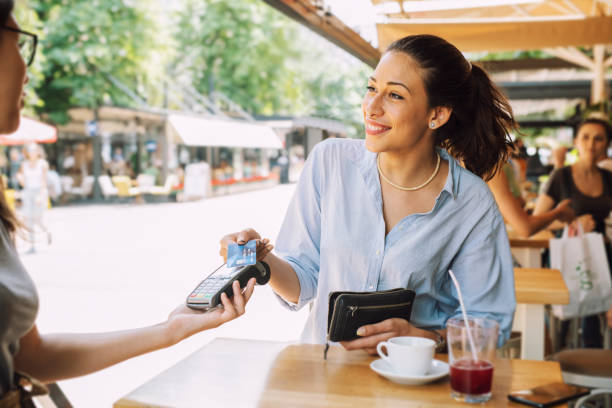 donna sorridente in un bar che paga con la sua carta. - carte da gioco foto e immagini stock