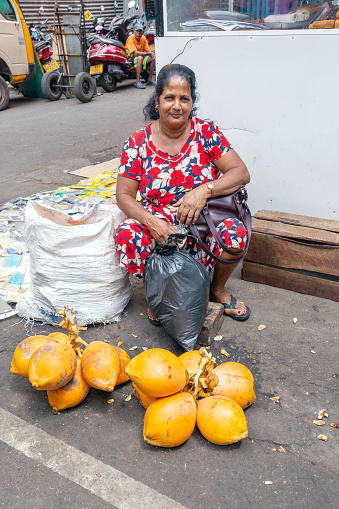 Colombo, Sri Lanka - February 5, 2020: A middle-aged woman sells coconuts on the street in Colombo