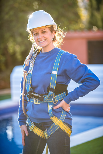 Portrait of Construction female worker wearing safety harness and safety line working at high place