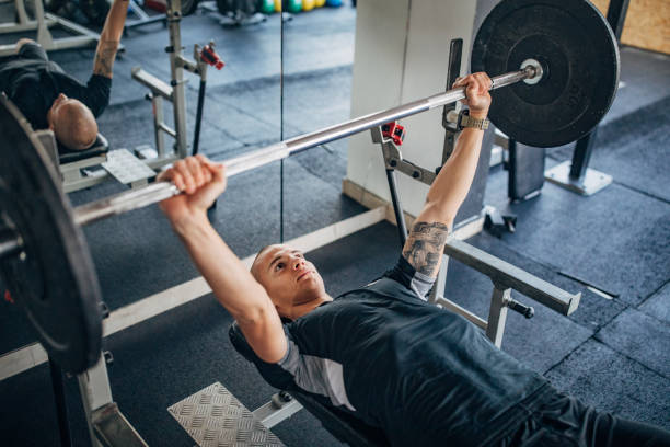 homem treinando na imprensa de banco - gym weight bench exercising weights - fotografias e filmes do acervo