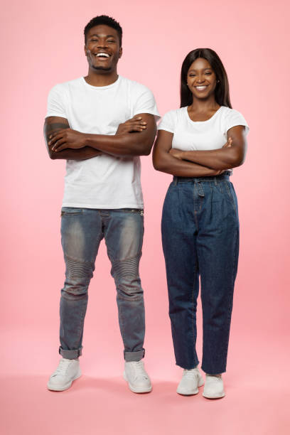 istock Confident couple standing with folded arms at pink studio background 1368582493