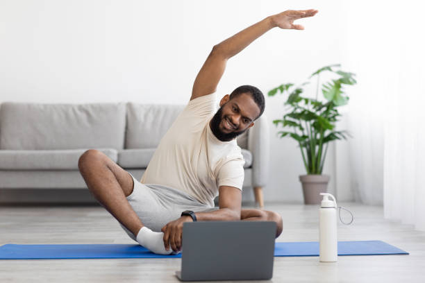 istock Happy young black bearded athlete man in white clothes do stretching or exercises for hands on mat 1368582508