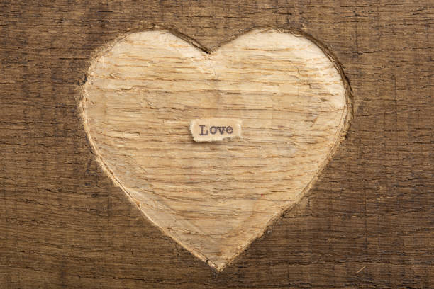 istock LOVE - tiny typed text note close up. Valentines Day greetings concept. Carved heart shape on wood as background for Valentines greeting card. 1368584472