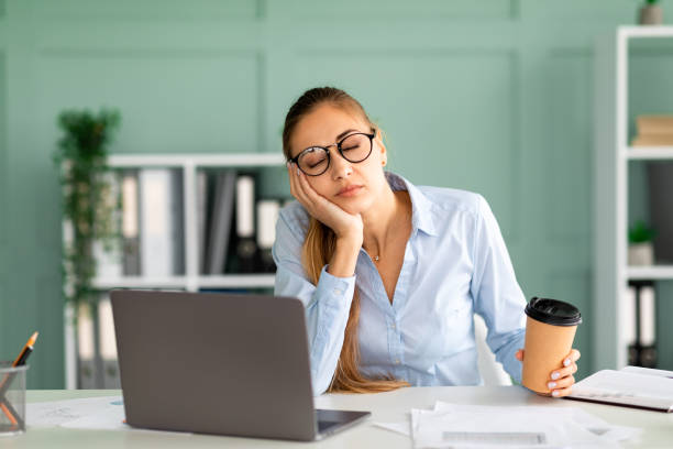istock Young businessman tired of computer work sleeping at workplace, holding coffee cup in hand 1368585821