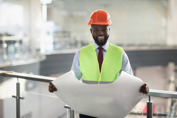 istock Happy african american man engineer holding paper drawing template 1368585996
